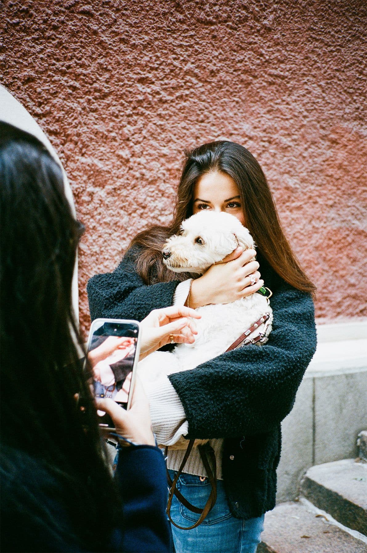 Tjej med vit hund i famn som fotas av en annan tjej